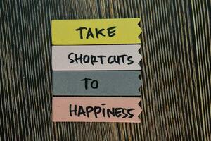 Take Shortcuts to Happiness write on sticky notes isolated on Wooden Table. Motivation or Insipiration Concept photo