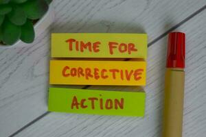Time For Corrective Action write on sticky notes isolated on Wooden Table. photo