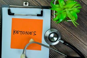 Concept of Ketones write on sticky notes with stethoscope isolated on Wooden Table. photo