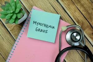 Concept of Myasthenia Gravis write on sticky notes isolated on Wooden Table. photo