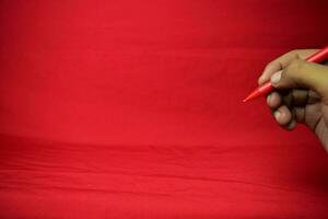 Man hand with red pen writing on red background photo