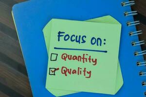 Concept of Quality is Important and Focus on Quality write on sticky notes isolated on Wooden Table. photo