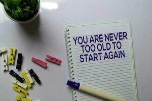You Are Never Too Old To Start Again text on a book at office desk. Motivation concept photo