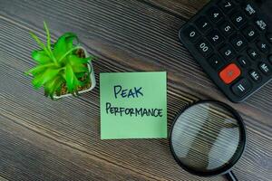 Peak Performance write on sticky notes isolated on Wooden Table. photo