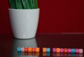 Stress or vacation text at colorful wooden block on red background. Desk office and education concept photo