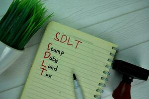 SDLT - Stamp Duty Land Tax write on a book isolated on office desk. photo