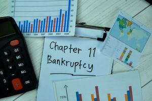 Concept of Chapter 11 Banktruptcy write on paperwork with statistics isolated on Wooden Table. photo