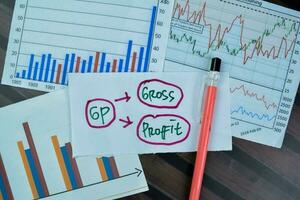 Concept of GP - Gross Profit write on sticky notes isolated on Wooden Table. photo
