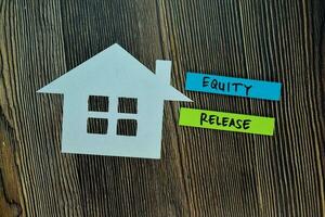 Equity Release write on sticky note and house made from paper isolated on Office Desk. Retirement concept photo