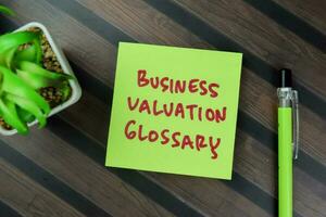 Concept of Business Valuation Glossary write on sticky notes isolated on Wooden Table. photo