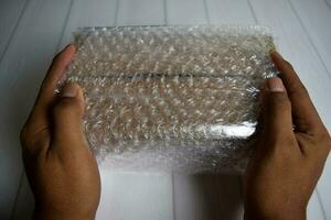 A young man holding bubble warp and box inside for protection delivery. photo