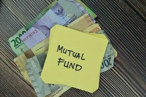 Concept of Mutual Fund write on sticky notes isolated on Wooden Table. photo