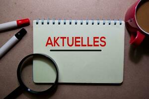 Aktuelles write on a book. for news and update. Isolated on Wooden Table photo