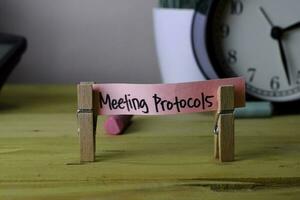 Meeting Protocols. Handwriting on sticky notes in clothes pegs on wooden office desk photo