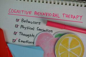Cognitive Behavioral Therapy write on a book with keywords isolated on Wooden Table. Chart or mechanism concept photo
