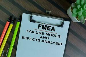 FMEA - Failure Modes and Effects Analysis write on a paperwork isolated on Wooden Table. photo