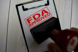 Close up Red Handle Rubber Stamper and text FDA Approved isolated on White Background. Selective focus on FDA Approved photo