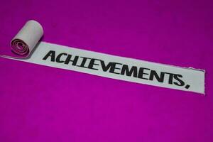 Achievements text, Inspiration and positive vibes concept on purple torn paper photo