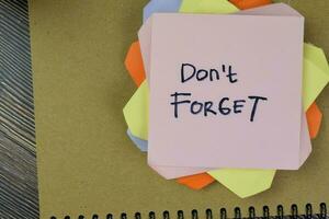 Concept of Don't Forget write on sticky notes isolated on Wooden Table. photo