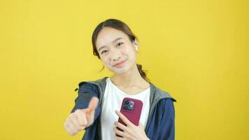 asiatisch Frau tragen Kopfhörer spielen mit Smartphone und zeigen genial Zeichen video