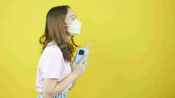 Close-up video of Asian woman wearing face mask holding smartphone and showing signs promoting products.