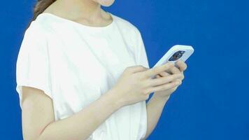 halvkropp video skott av asiatisk kvinna använder sig av mobil telefon på gul bakgrund.