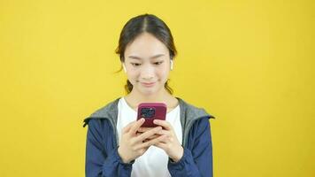 asiático mujer en auriculares sonriente brillantemente y mirando mediante vídeo cámara video