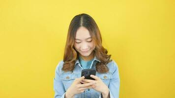 Asian woman holding a smartphone with long blue hair wearing colored jeans smiling happily and optimistically. video