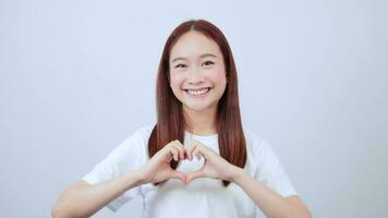asiatisch Frau erziehen ihr Hände über ihr Kopf Herstellung ein Herz Zeichen, suchen beim das Vorderseite. video