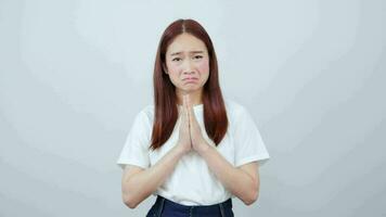 Video footage of a desperate brown-haired woman clenching her palms together and looking with a pleading expression on her face, begging for help.