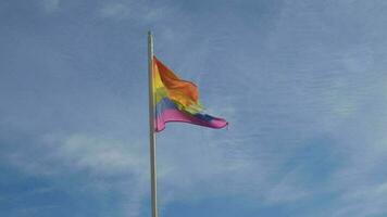 homo trots regenboog vlag golvend Aan blauw lucht achtergrond. symbool van de lgbt gemeenschap Aan een trots. menselijk rechten, Gelijk rechten, vrede en vrijheid. ondersteuning lgbtq gemeenschap video