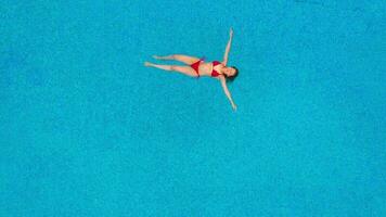 View from the top as a woman in a red swimsuit swims in the pool video