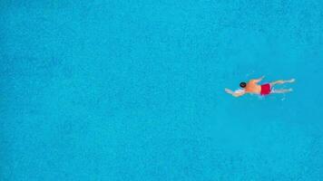 Aerial view of a man in red shorts swimming in the pool video