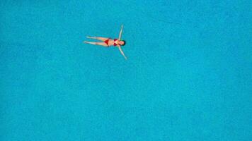 View from the top as a woman in a red swimsuit swims in the pool video