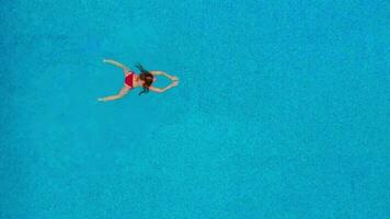 Aussicht von das oben wie ein Frau im ein rot Badeanzug schwimmt im das Schwimmbad video