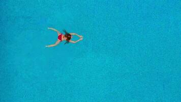 vue de le Haut comme une femme dans une rouge maillot de bain nage dans le bassin video