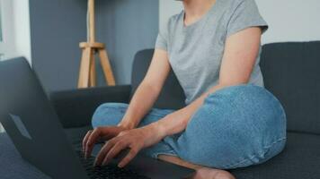 Frau Sitzung auf ein gemütlich Sofa und Arbeiten auf ein Laptop und Smartphone. Konzept von Fernbedienung arbeiten. Zuhause Büro video