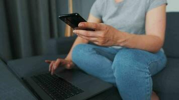 Woman sitting on a cozy sofa and working on a laptop and smartphone. Concept of remote work. Home Office video
