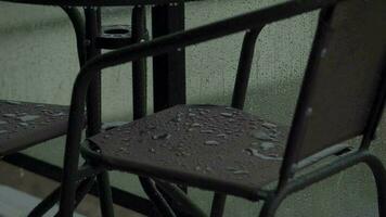 zwaar regen giet naar beneden de meubilair Aan de balkon of terras. druppels rennen naar beneden de glas van de hek video