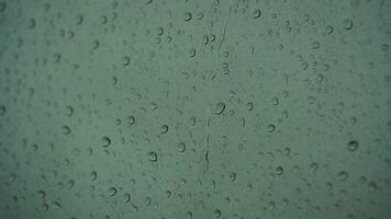 schließen oben von ein Glas mit Wasser Tropfen während draußen ist regnen. Tropfen von Regen durch Glas. video
