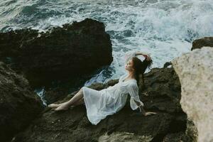 attractive woman with long hair lying on rocky coast with cracks on rocky surface view from above photo