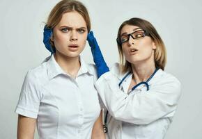 A nurse in blue gloves examines a patient in a white T-shirt on a light background photo