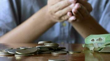 el manos pobre rural chico poniendo monedas en ambos lados el mesa de madera mesa, en un económico recesión me gusta hoy, ahorro dinero es un importante importar ese debería no ser pasado por alto., ahorros concepto video