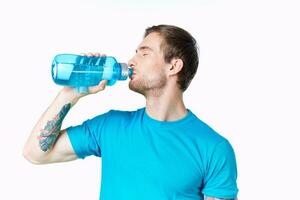 guy athlete drinks water from a bottle on a white background and a blue t-shirt photo