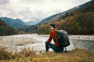 woman with backpack by the river mountain landscape autumn dry grass model photo