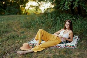 Young beautiful hippie woman lying on the ground in nature in the fall in eco clothes in yellow pants in the sunset light photo