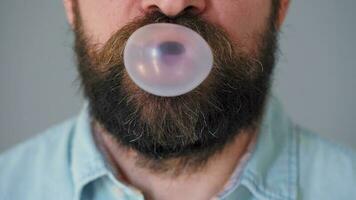 barbado hombre mastica masticación goma y infla un burbuja fuera de él. malo hábito concepto video