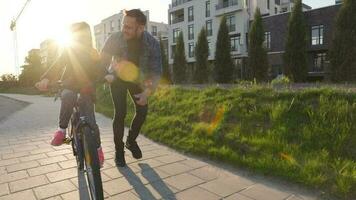 papá es enseñando hija cómo a paseo bicicleta a puesta de sol video