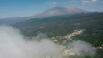 Flying above the clouds over the island of Tenerife - a view of the settlements and the Teide volcano. Canary Islands video