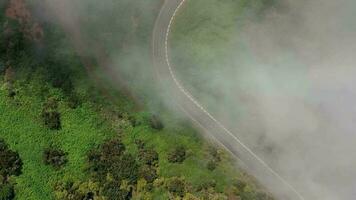 vliegend door de wolken over- een leeg berg weg omringd door groen vegetatie video